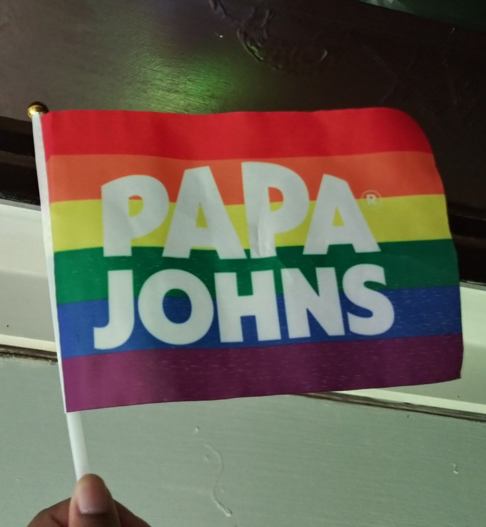 Image of small rainbow flag, with "Papa Johns" in bold white letters on the front