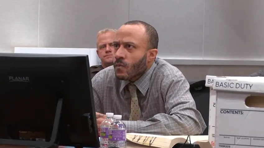 Darrell Brooks sits in the courtroom wearing a button-up shirt and tie, angrily glaring at the judge offscreen.
