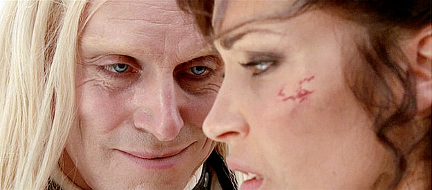 A close-up of Kansa leering at a woman, with a creepy smile on his face.