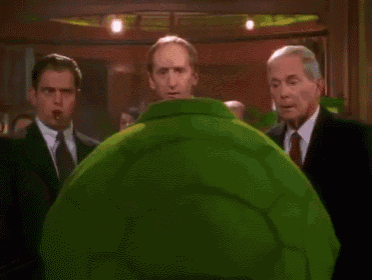 A scene from the movie 'Master of Disguise' featuring the character Pistachio Disguisey dressed as a turtle, biting a man's nose off, then spitting it back onto his face.