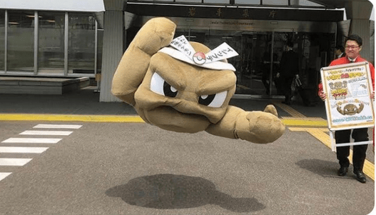 The same person in the Geodude costume appears to float in mid-air outside the same building. The legs were edited out.