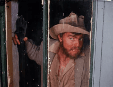 Animated GIF of Torgo, a scraggly looking man with a beard and mustache holding a staff with a hand on top. He stares lustfully through a window, squirming around and licking his lips.